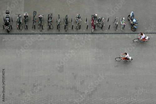Vogelperspektive auf eine Reihe von geparkten Fahrrädern und Motorrädern und zwei Radfahrer