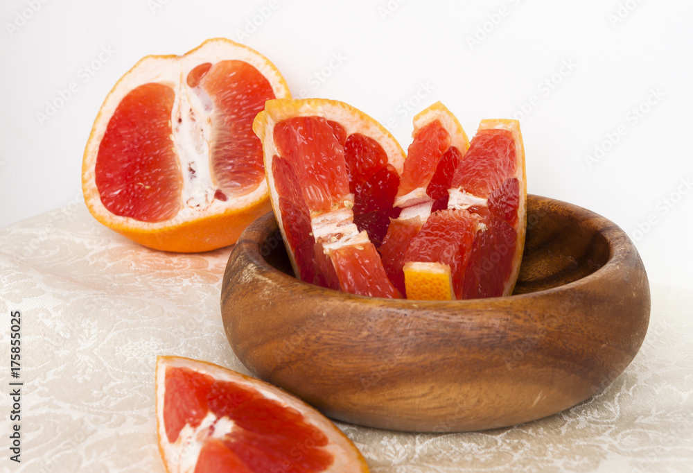 Sliced grains of grapefruit close-up in a wooden plate Sliced grains of grapefruit close-up in a wooden plate