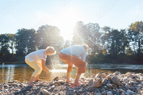 Two senior people enjoying retirement and simplicity while throwing stones into the river photo
