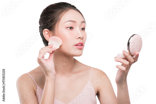 Portrait of beautiful young asian woman with perfect fresh clean skin applying cosmetic brush and use mirror.