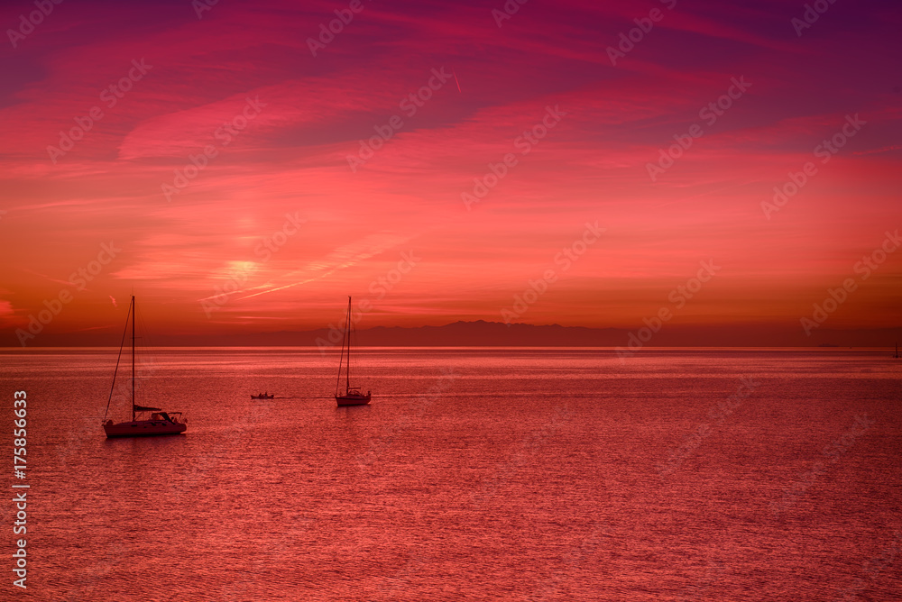 Beautiful colorful sunset at the sea with two sailing boats . Beauty world natural outdoors travel background Beautiful colorful sunset at the sea with two sailing boats . Beauty world natural outdoors travel background