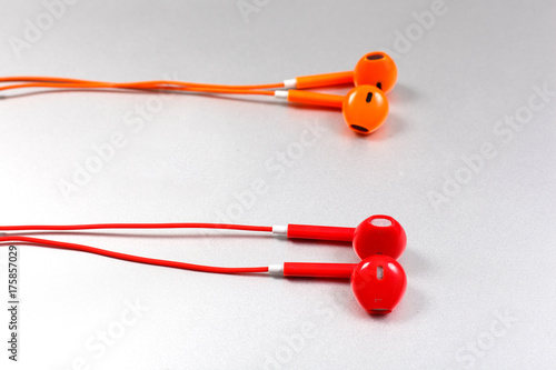 Orange and red color earphone with laptop on white background.