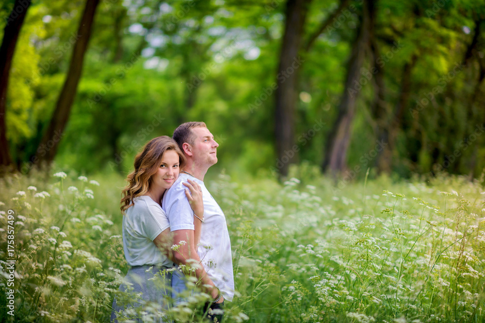 happy young couple walking in the evening park, gently hugging and smiling happy young couple walking in the evening park, gently hugging and smiling