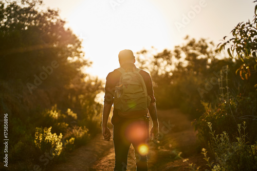 male millennial hiker trekking up trail in southern california during sunset