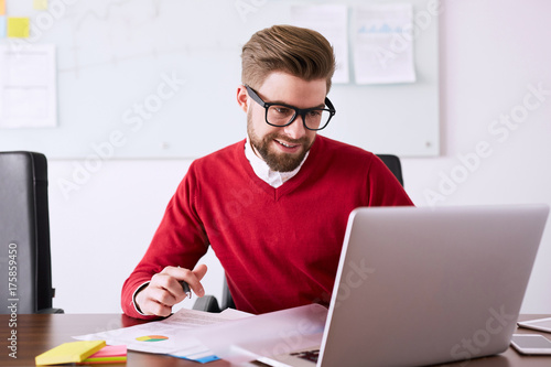 Young businessman working in office using laptop and business documents