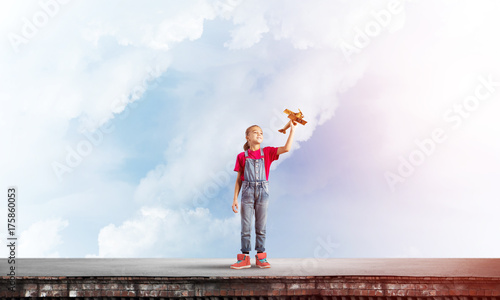 Concept of careless happy childhood with girl dreaming to become pilot