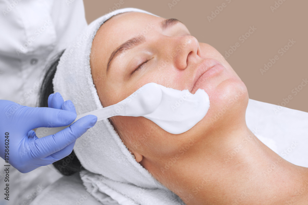 The cosmetologist for procedure of cleansing and moisturizing the skin, applying a Alginic mask to the face of a young woman in beauty salon.Cosmetology and professional skin care.