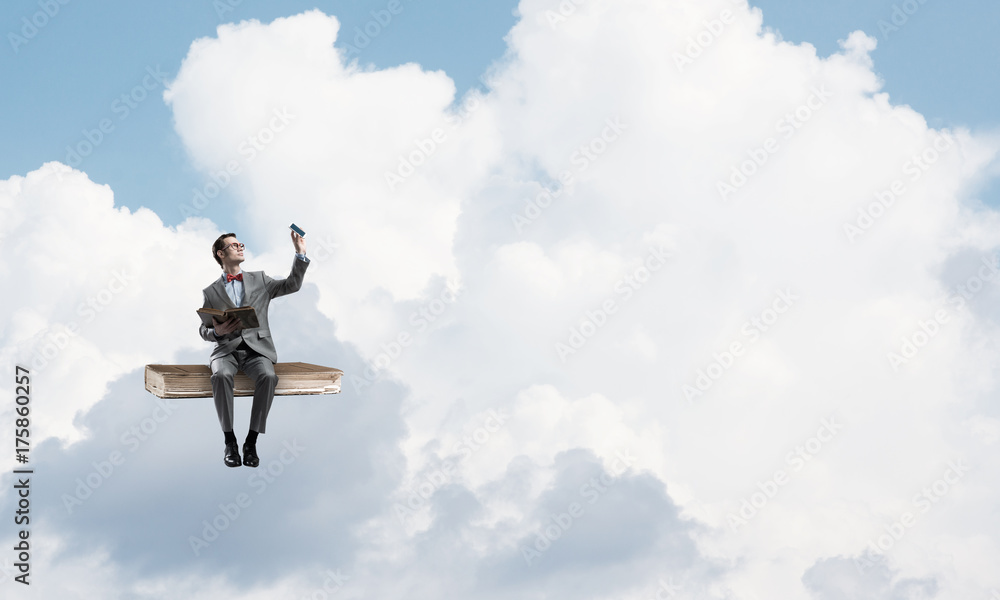 Young businessman or student floating in blue sky and studying the science