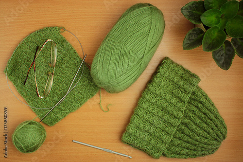 needlework, knitting needles and crochet, hat of light green thread, home flower