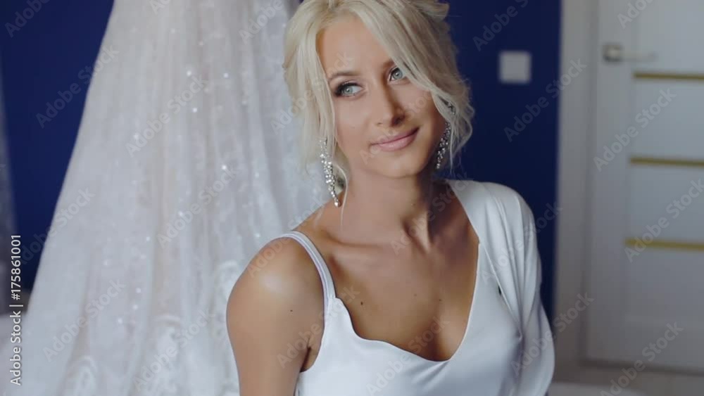 The portrait of the young bride at a window - the girl prepares for a wedding and dresses accessories, earrings. The face of the blonde with a stylish hairstyle The portrait of the young bride at a window - the girl prepares for a wedding and dresses accessories, earrings. The face of the blonde with a stylish hairstyle