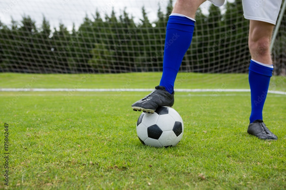 Low section of soccer player with ball on field