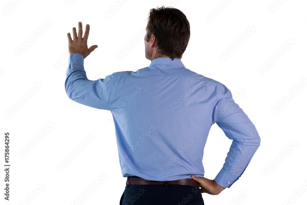 Rear view of businessman with hand on hip using invisible Rear view of businessman with hand on hip using invisible