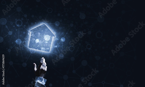 Conceptual image with hand pointing at house or main page icon on dark background © adam121