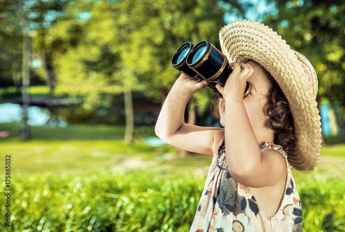 Happy little kid looking around with a vintage binoculars