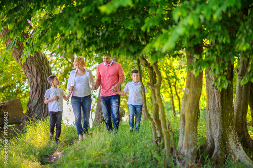 happy family on a walk in a beautiful evening park, amicably hold hands and walk along the trail