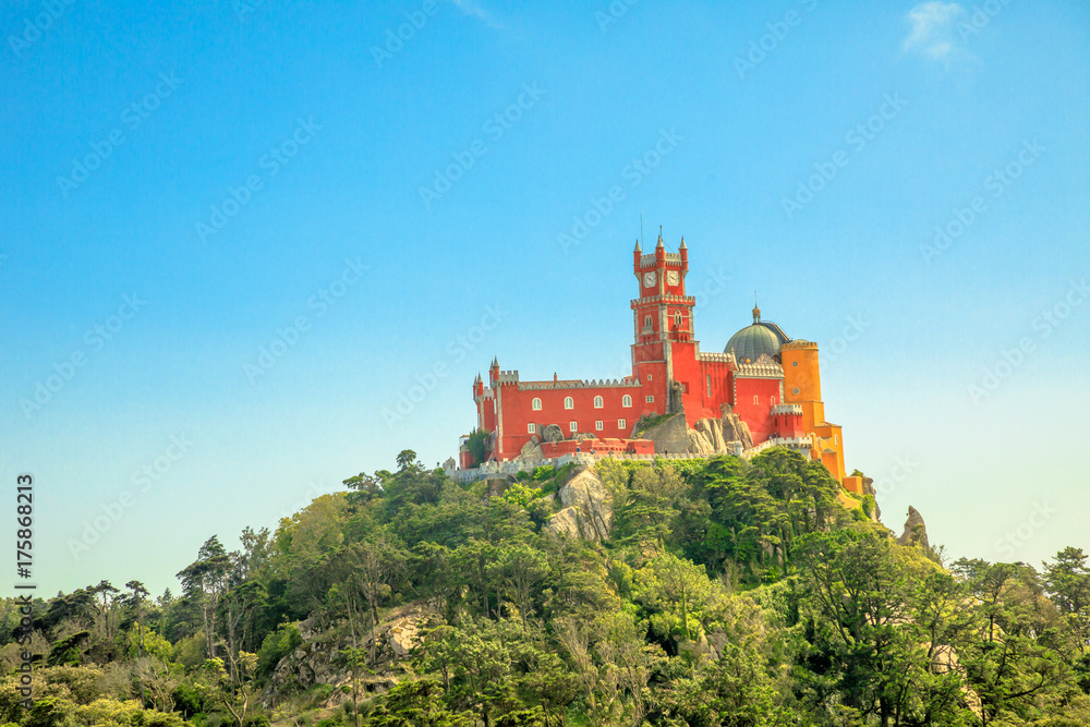 Aerial view of colorful Pena Palace on top of a hill above Sintra in asunny day with blue sky. Panorama of Palacio da Pena, a National Monument, Unesco Heritage and one of Seven Wonders of Portugal.