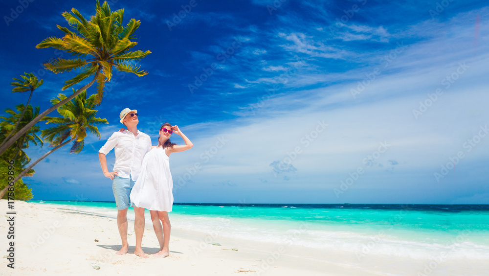 happy young couple in white clothes having fun by the beach happy young couple in white clothes having fun by the beach