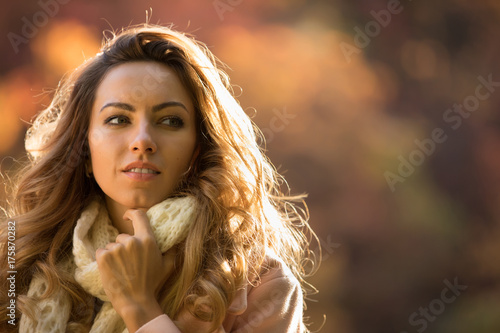 Close up portrait of cute woman in autumn day at park look at side, blurred background