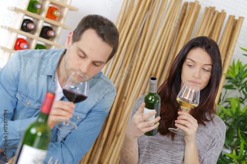 happy young couple tasting wine with merchant in foreground