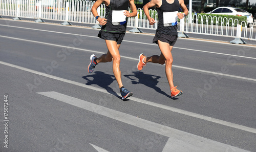 Marathon runners running on city road © lzf