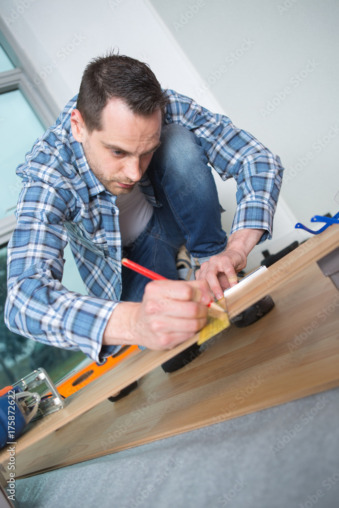 Man marking position on floorboard Man marking position on floorboard