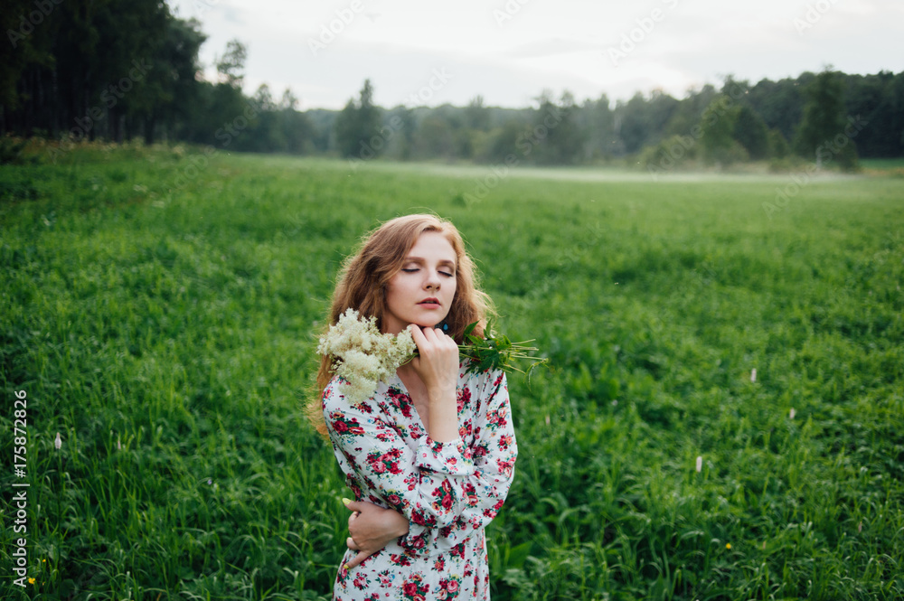 A beautiful girl in a colorful dress stands in the evening on a meadow against a background of fog. A beautiful girl in a colorful dress stands in the evening on a meadow against a background of fog.