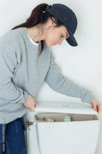 confident woman repairing toilet flush