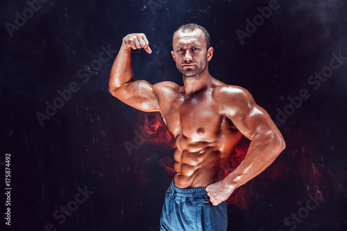 Strong bald bodybuilder with six pack. Strong bodybuilder man with perfect abs, shoulders,biceps, triceps and chest, personal fitness trainer flexing his muscles © zamuruev