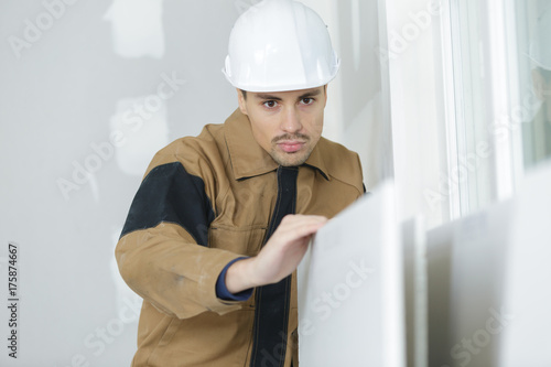 Konstfotografi young builder sanding the door before refinishing at home