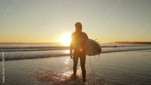 Silhouette of a surfer entering the ocean at sunset, Costa Caparica, Portugal