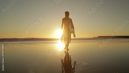 Silhouette of a surfer entering the ocean at sunset, Costa Caparica, Portugal