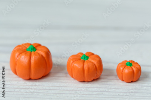 Three little polymer clay pumpkins on white wooden background