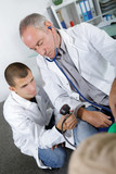 older doctor training young doctor on measuring pressure
