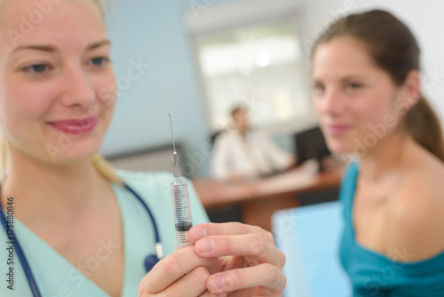 Nurse preparing syringe for female patient