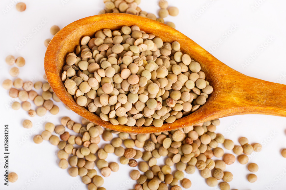 Pile of green lentils in a wooden spoon isolated on white background. Pile of green lentils in a wooden spoon isolated on white background.