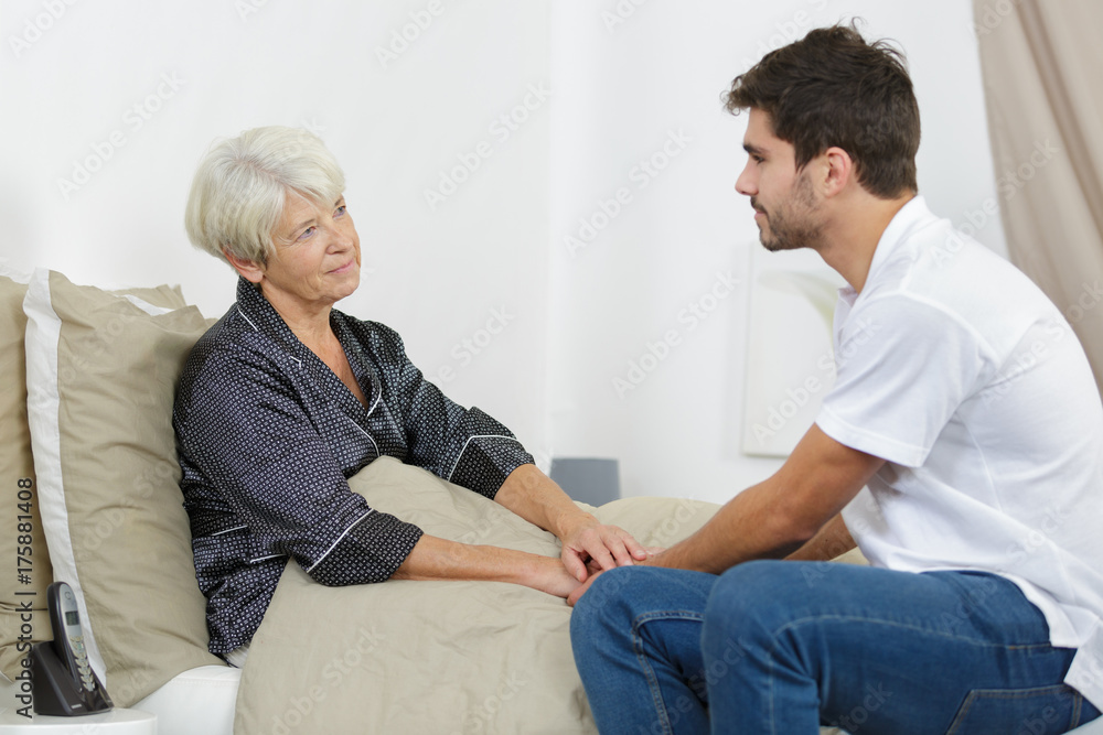 Obraz premium old lady on bed being looked after by grandson