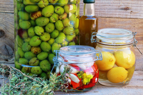 Fermented vegetables in jars. Vegetarian food concept. Lemons, olives, peppers, chillies, olive oil, oregano