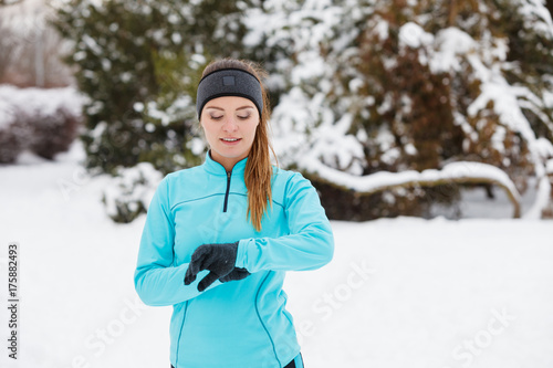 Winter workout. Girl wearing sportswear, looking at watch