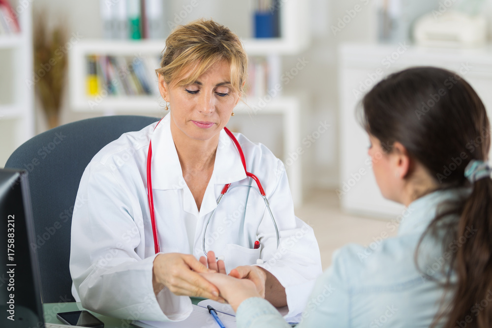 mature female doctor looking at her patients hands mature female doctor looking at her patients hands