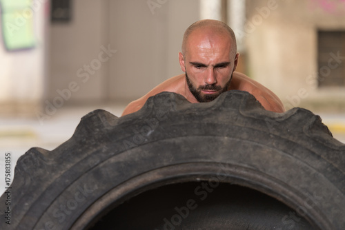 Muscular Man Exercising Crossfit Workout By Tire Flip