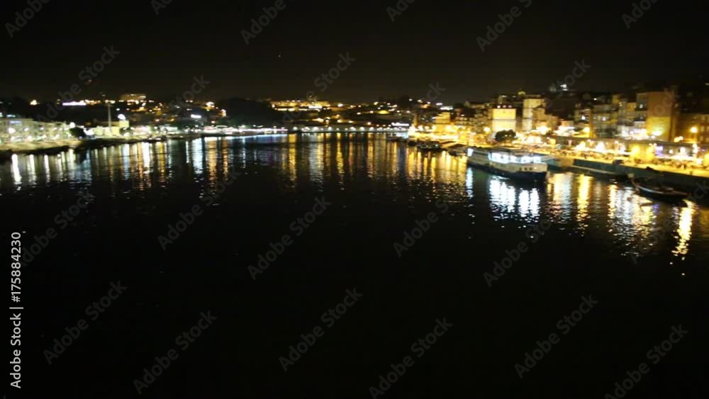 traditional Rabelo boat, used for transportation of port wine from Douro Valley, to wine cellars in Vila Nova de Gaia. Ribeira waterfront illuminated by night of Porto, Portugal