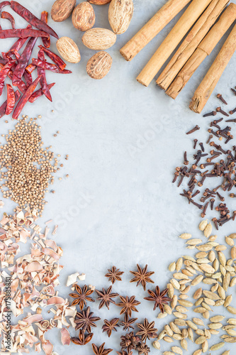 Different kinds of aromatic winter spices on gray concrete background, top view, copy space, vertical
