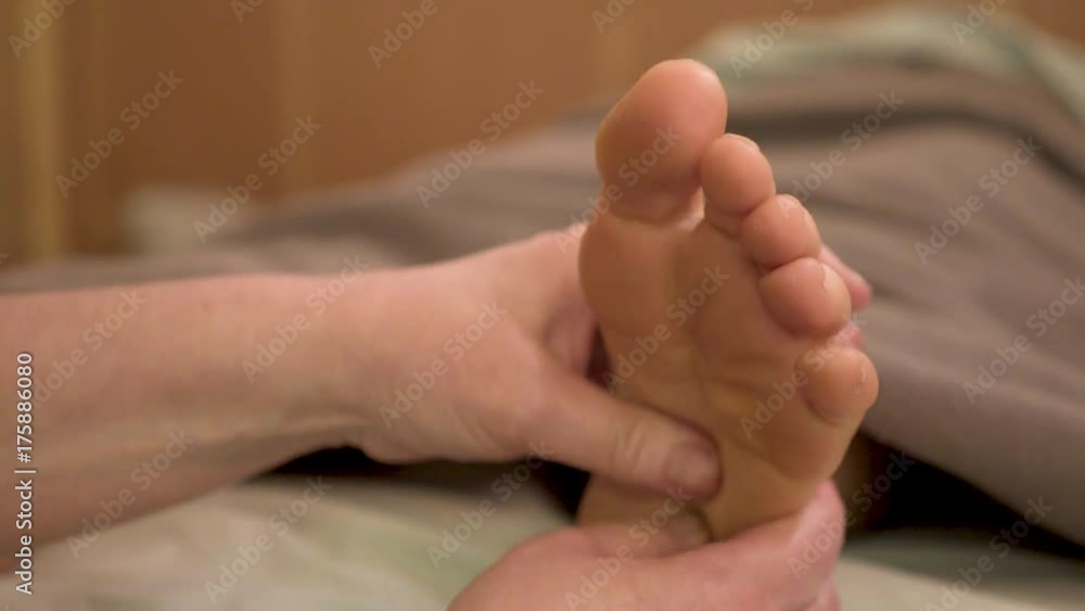 Using her thumbs, a massage therapist works on the arch of a foot of a caucasian woman for deep tissue massage. Using her thumbs, a massage therapist works on the arch of a foot of a caucasian woman for deep tissue massage.