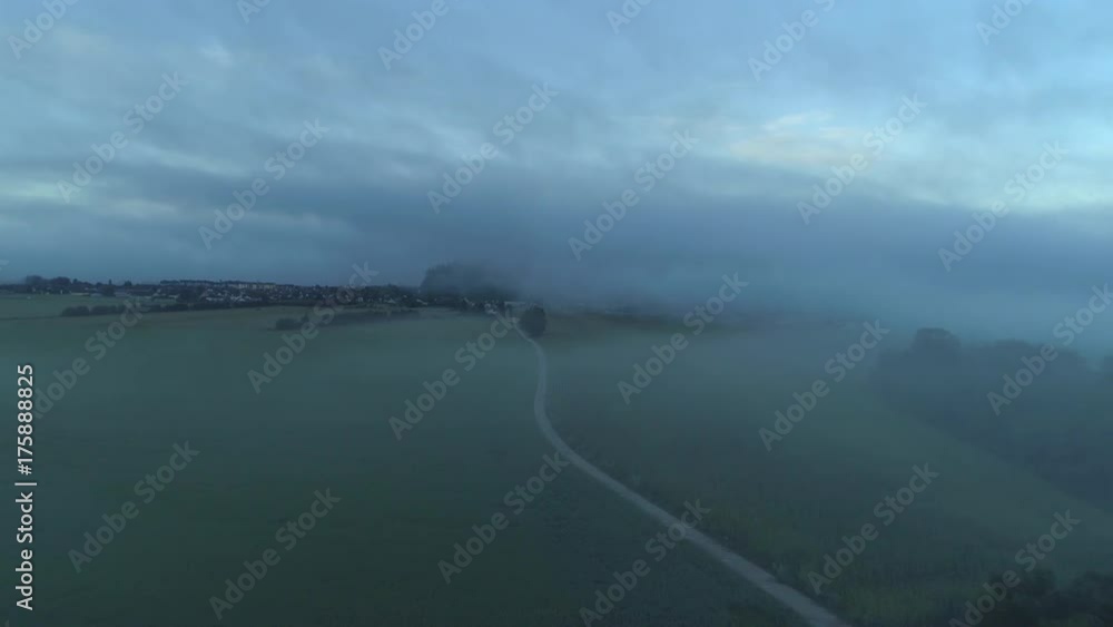 AERIAL: Creepy empty road leading though dark foggy agricultural fields before sunrise. Scary country road leading past the misty forest and spooky foggy fields at dusk. Scary misty scenery AERIAL: Creepy empty road leading though dark foggy agricultural fields before sunrise. Scary country road leading past the misty forest and spooky foggy fields at dusk. Scary misty scenery