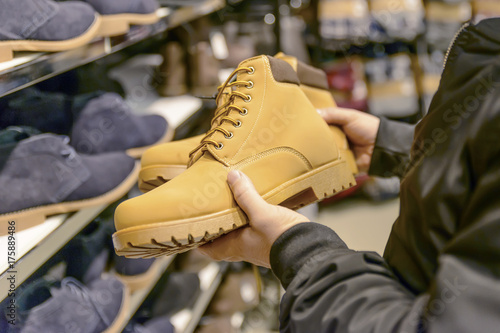 young man with short hair chooses his shoes with a good mood 