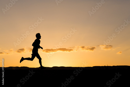 Silhouette of a man running at sunset