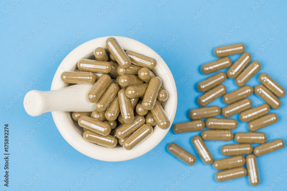 herbal capsule and mortar on bluee background. Alternative medicine concept herbal capsule and mortar on bluee background. Alternative medicine concept