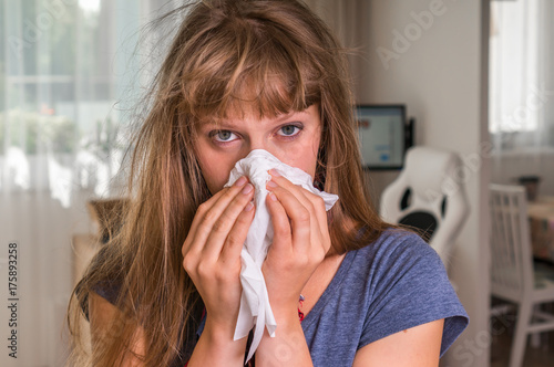 Sick woman with flu or cold sneezing into handkerchief