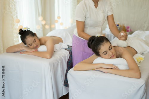 Two cute young women enjoy relaxing during massage at spa.