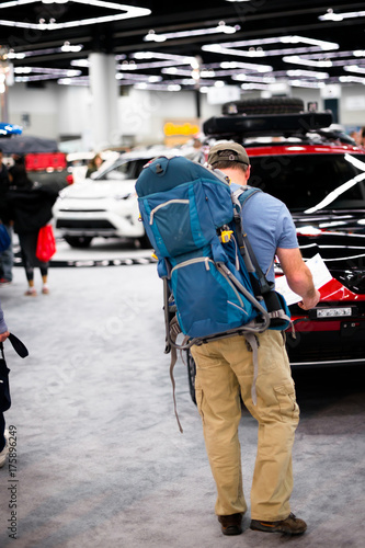 Man with tourist backpack examines map of cars exhibition